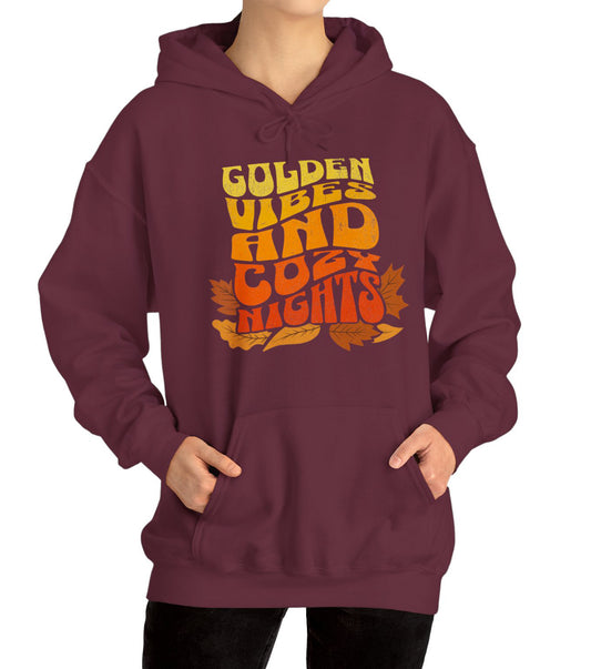 Comfy hoodie with “Golden Vibes and Cozy Nights” text in yellow-to-orange gradient and autumn leafs BimBangDesign